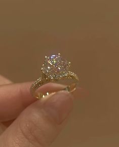 a person holding a diamond ring in their hand with the engagement ring on it's finger