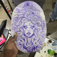 a person is holding up a paper plate with a drawing of a woman's face on it