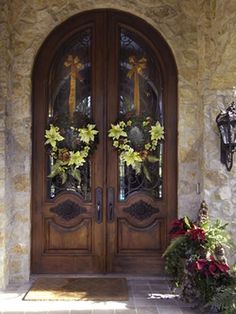 the front door is decorated with wreaths and flowers on it's glass panels