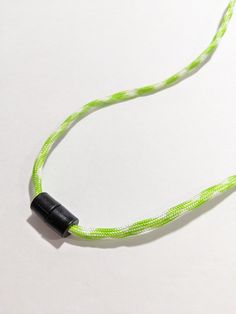 a green and white cord with a black object on it