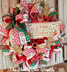 a christmas wreath with gingerbreads and red bows on the front door, hanging from a wooden wall