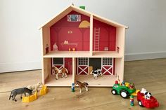 a toy farm house with horses and cows in the yard next to it on top of a hard wood floor