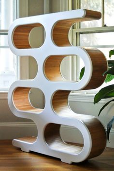 a white shelf sitting next to a potted plant on top of a hard wood floor