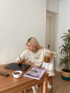 a woman sitting at a table writing on a piece of paper and holding a pen