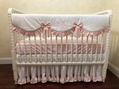 a white crib with pink ruffles and a monogrammed pillow