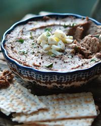 a bowl of hummus and crackers on a wooden table