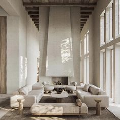 a large living room with white couches and wooden beams on the ceiling, along with tall windows