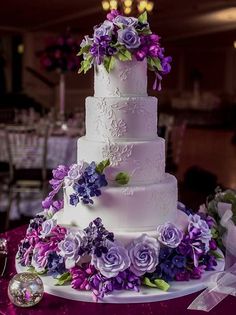 a white wedding cake with purple flowers on it