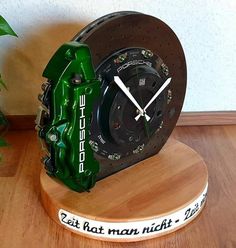 a green clock sitting on top of a wooden table next to a potted plant