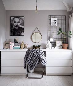 a white dresser with pictures on the wall and a blanket draped over it in front of a mirror