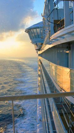 the deck of a cruise ship looking out over the ocean at sunset or sunrise with clouds in the sky