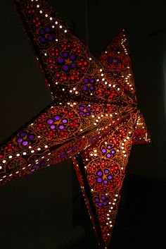 a large star shaped object is lit up in the dark with red and purple lights