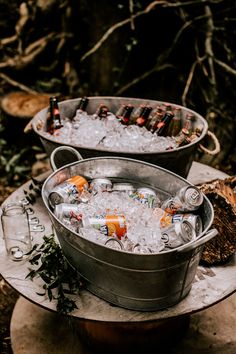 two metal buckets filled with drinks sitting on top of a table