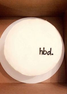 a white cake in a box with the word hbd on it's side