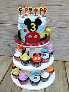 a three tiered mickey mouse cake with cupcakes