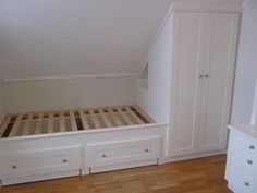 an empty bedroom with white furniture and wood flooring