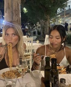 two women sitting at a table eating spaghetti