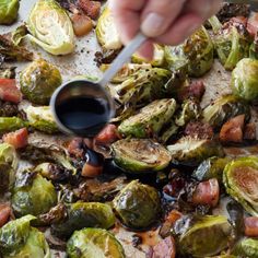 someone is dipping sauce on top of roasted brussel sprouts with bacon