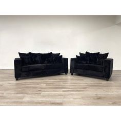 two black couches sitting on top of a hard wood floor next to each other