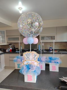 some balloons are on top of boxes in the middle of a kitchen counter with blue and pink tulle