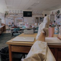 a person's feet resting on a desk in a classroom