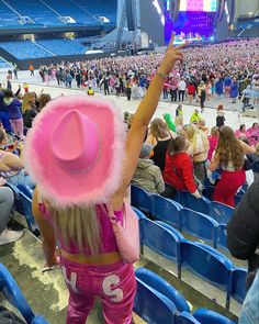 a woman in pink is holding up her cell phone at a sporting event with people watching