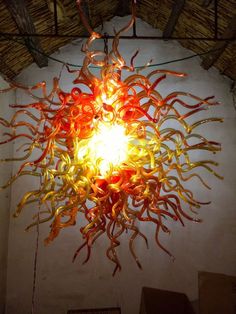 a chandelier made out of blown glass with red and yellow swirls hanging from the ceiling