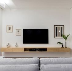 a flat screen tv mounted to the side of a wall above a couch in a living room