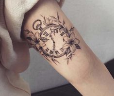 a woman's arm with a clock and flowers tattoo design on the left forearm