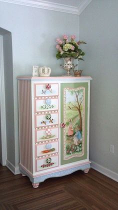 an ornate painted dresser with flowers and pictures on the door knobs is shown in this room