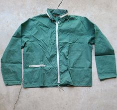 Discover a unique piece of history with this vintage 70's Thin Green Montgomery Ward Windbreaker with a tucked rain hood. This lightweight jacket is great for the outdoors or any rainy day in a city. Introducing a unique piece of history: a vintage 70's Thin Green Montgomery Ward Windbreaker with a tucked rain hood. This lightweight jacket is perfect for outdoor adventures or staying dry on a rainy day in the city. Measurements: - Tag: XL - Pit to Pit: 26" - Length: 28" - Cuff to Pit: 19" This item may have some flaws due to its vintage nature. While we will make note of any significant flaws, we kindly ask for your understanding and expectation of imperfections. This item is part of our 'recycled vintage' collection, meaning it has been previously owned and has a unique history. Rainy Day In The City, Montgomery Ward, On A Rainy Day, Vintage Nature, A Rainy Day, Lightweight Jacket, Track Jackets, Vintage Tees, Hoodie Jacket