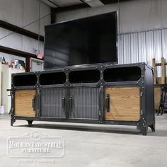 an entertainment center in a warehouse with metal and wood accents, large screen television on top