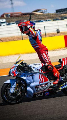 a man riding on the back of a red and white motorcycle down a race track