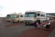 people sitting in lawn chairs next to parked rvs