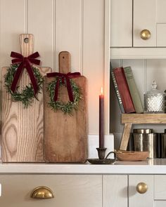 two wooden cutting boards sitting on top of a kitchen counter next to candles and books