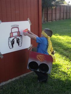 a young boy holding up a paper cut out of a construction truck