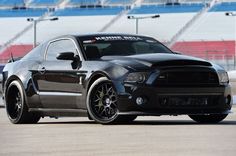 a black mustang is driving on the track