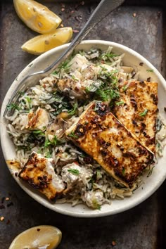 grilled tofu and rice with lemon wedges on the side in a white bowl