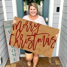 a woman holding up a merry christmas sign