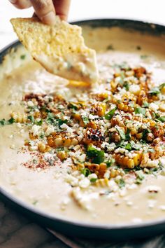 a person is dipping some food into a skillet with cheese and other toppings