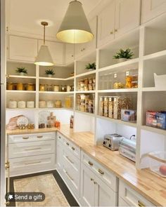 a kitchen filled with lots of white cupboards and counter top space next to a light fixture