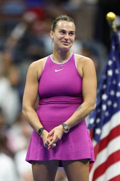 a female tennis player in a purple dress and an american flag on the sidelines