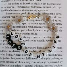 a bracelet with letters and beads on top of an open page in a book,