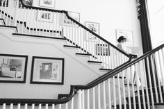 a woman is walking down the stairs in a house with pictures on the wall behind her