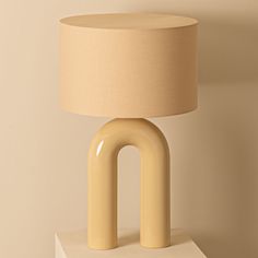 a table lamp sitting on top of a white block next to a beige light shade