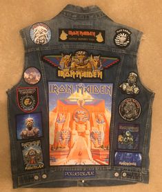 an iron maiden denim vest with patches on the front and back, hanging up against a wall