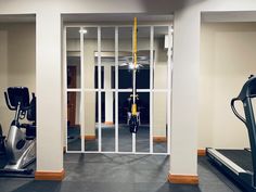 an empty gym with treadmills and exercise equipment in the foreground, through glass doors