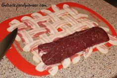 a piece of meat sitting on top of a red cutting board next to a knife