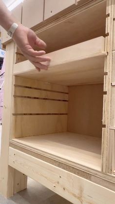 a person is reaching for the bottom shelf of a cabinet