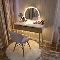 a white chair sitting in front of a desk with a mirror and lights on it